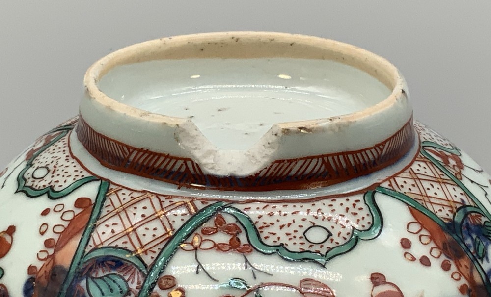 An antique deep circular porcelain bowl featuring hand-painted Chinese Imari floral foliage and diaper pattern borders in blue, red, and green. View X