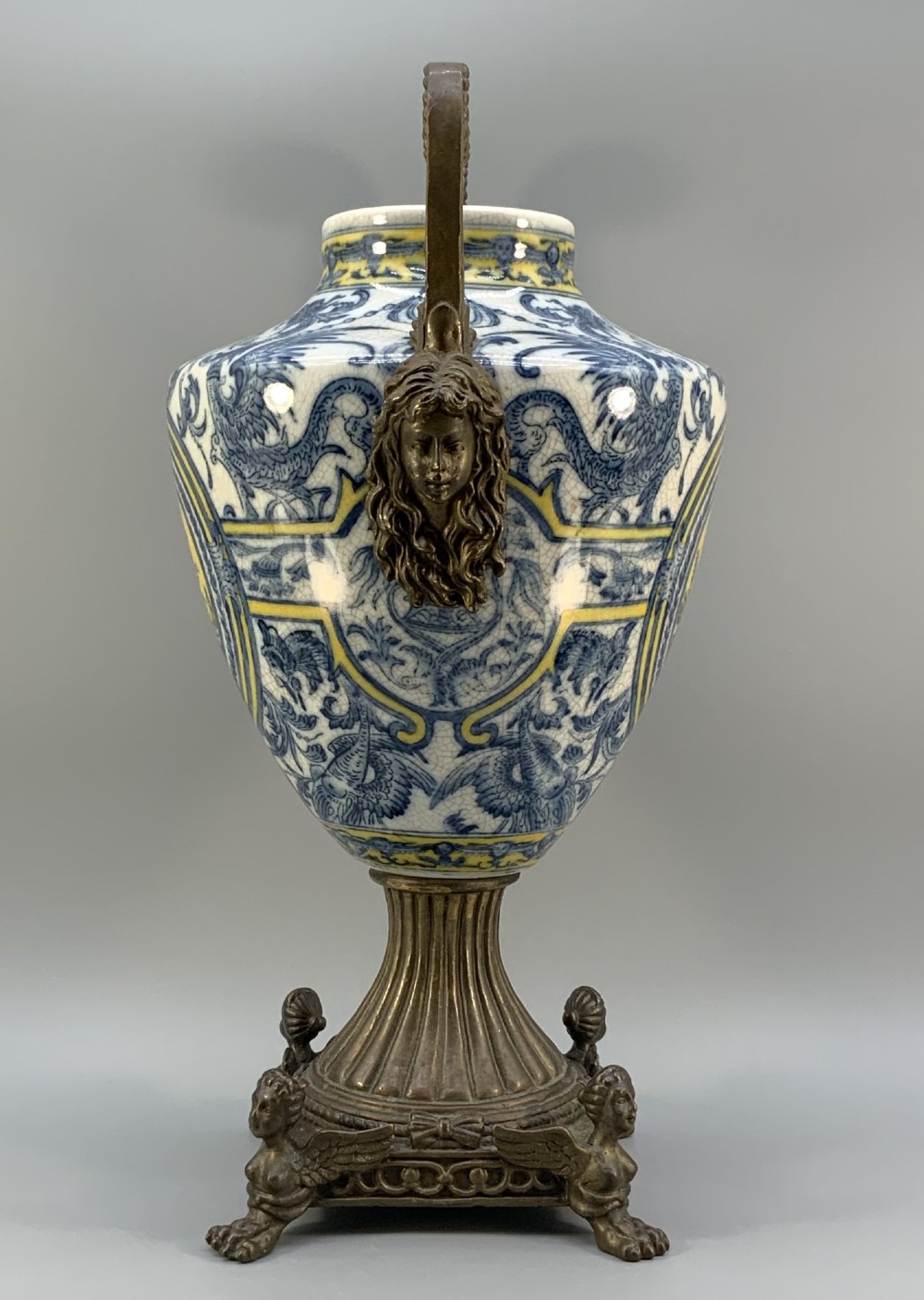 A Renaissance Revival faience vase featuring blue and yellow glazed classical medallion artwork mounted on a cast bronze footed base with mask handles. View VII