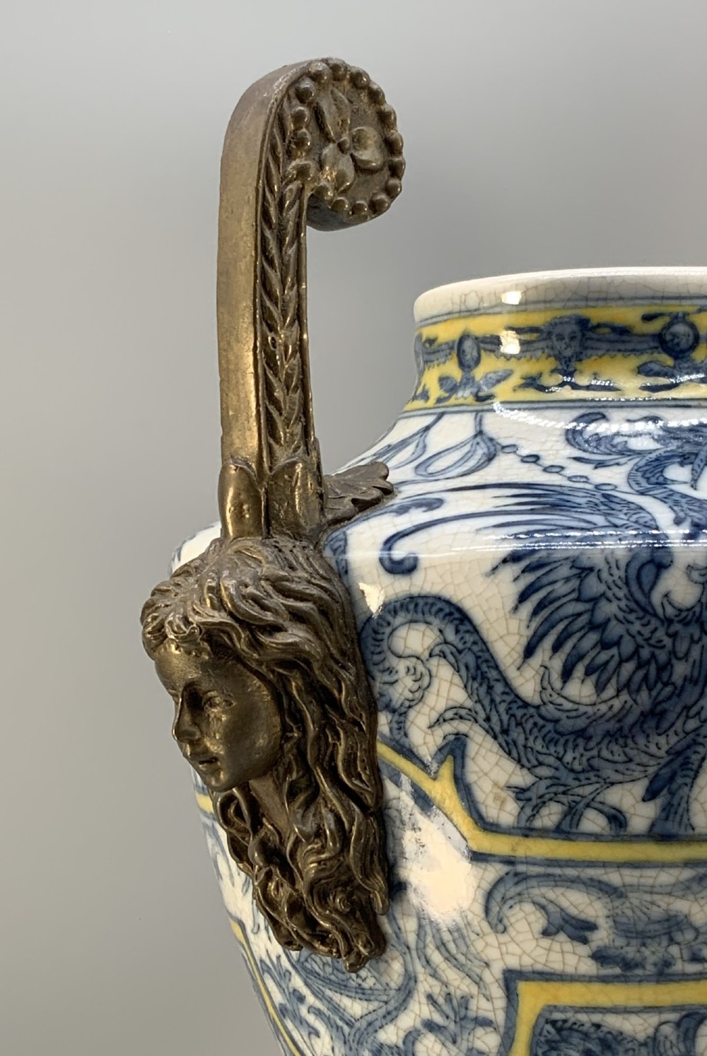 A Renaissance Revival faience vase featuring blue and yellow glazed classical medallion artwork mounted on a cast bronze footed base with mask handles. View XI