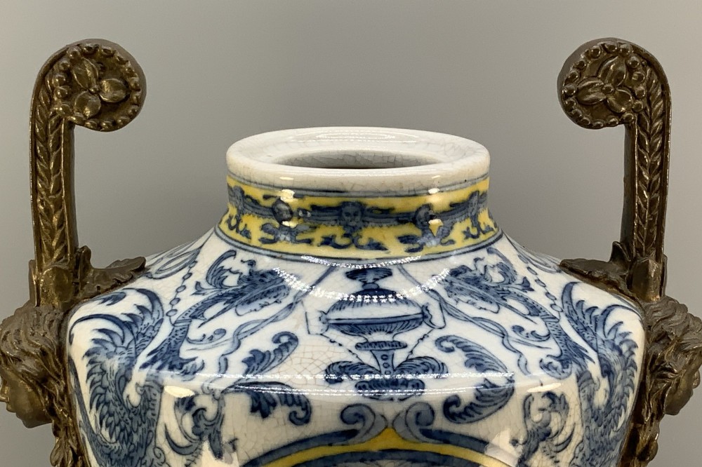 A Renaissance Revival faience vase featuring blue and yellow glazed classical medallion artwork mounted on a cast bronze footed base with mask handles. View XIII