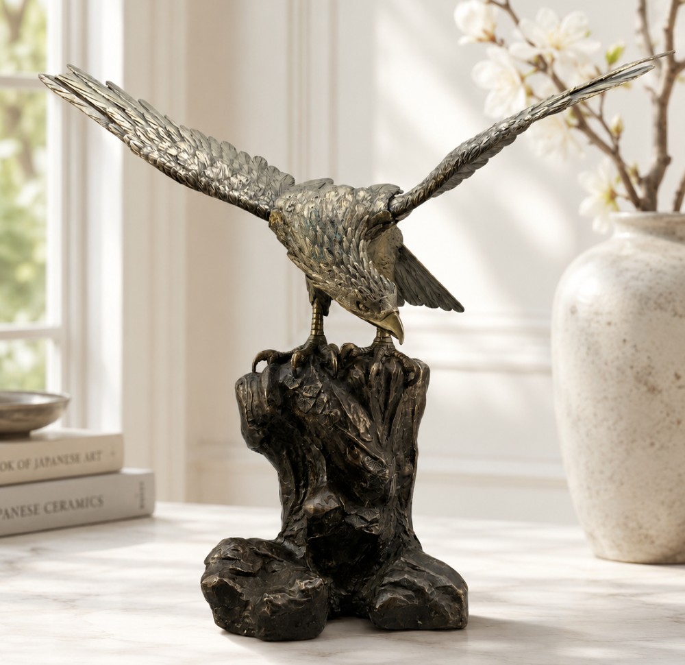 A dark bronze sculpture depicting an eagle with outstretched wings perched on a rocky base. View II
