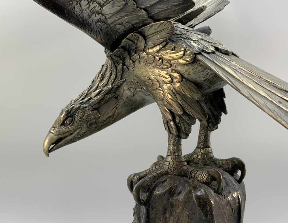 A dark bronze sculpture depicting an eagle with outstretched wings perched on a rocky base. View VIII