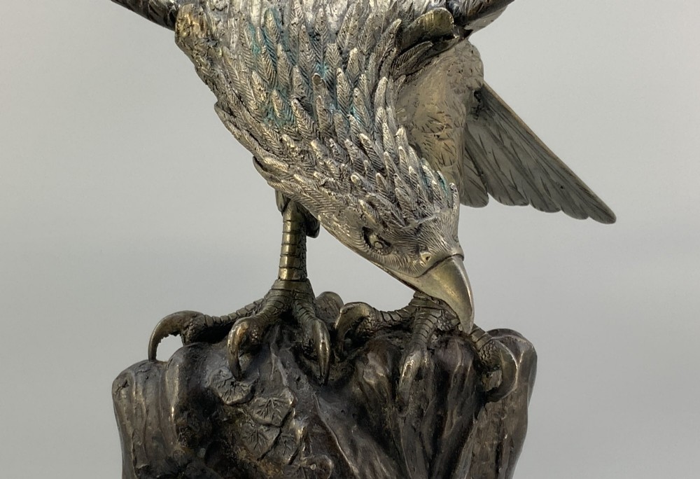 A dark bronze sculpture depicting an eagle with outstretched wings perched on a rocky base. View XI