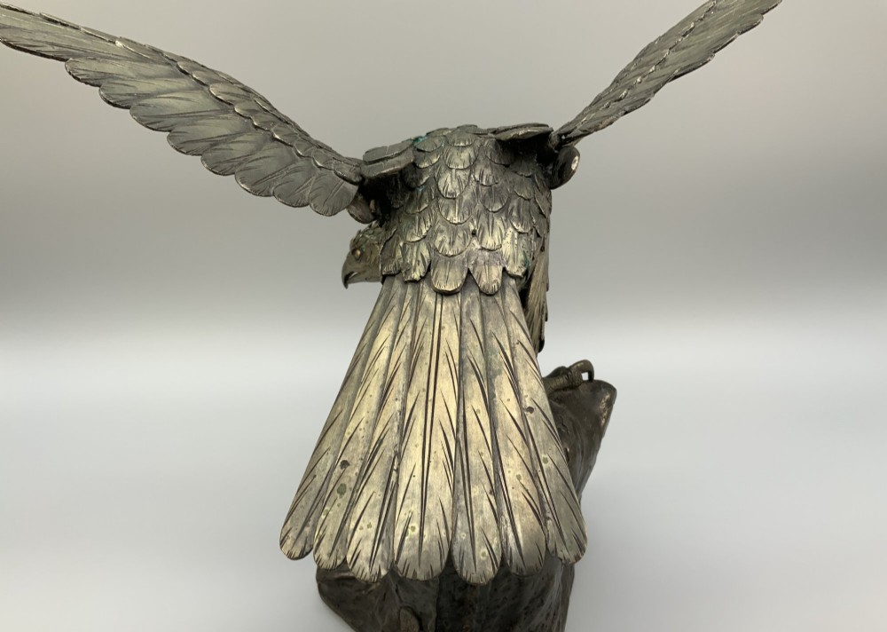 A dark bronze sculpture depicting an eagle with outstretched wings perched on a rocky base. View XIII