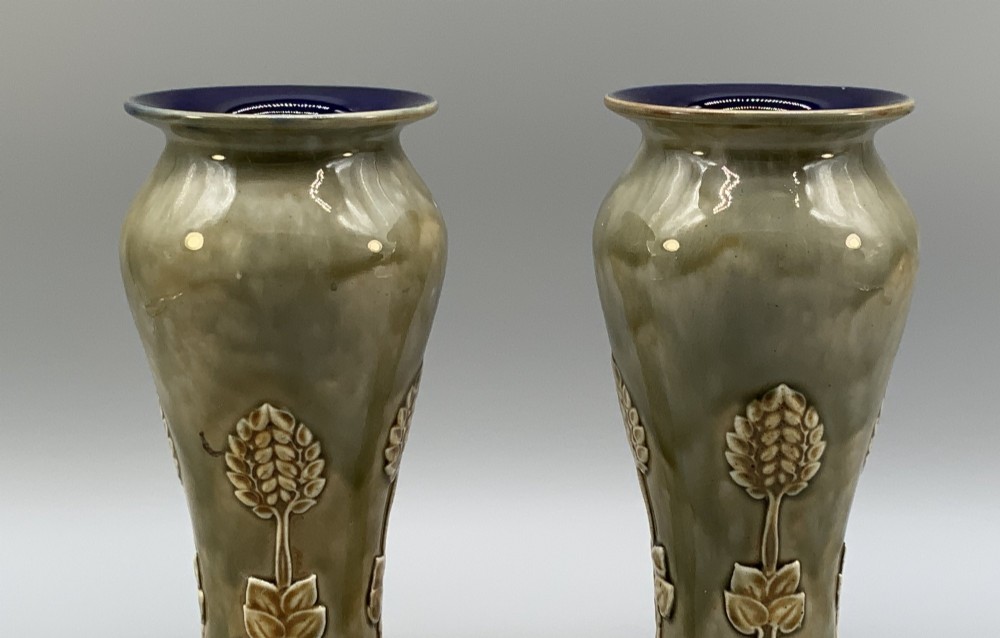 A matched pair of Royal Doulton Lambeth Art Nouveau stoneware vases featuring raised relief botanical motifs on a muted olive green glazed ground. View IV