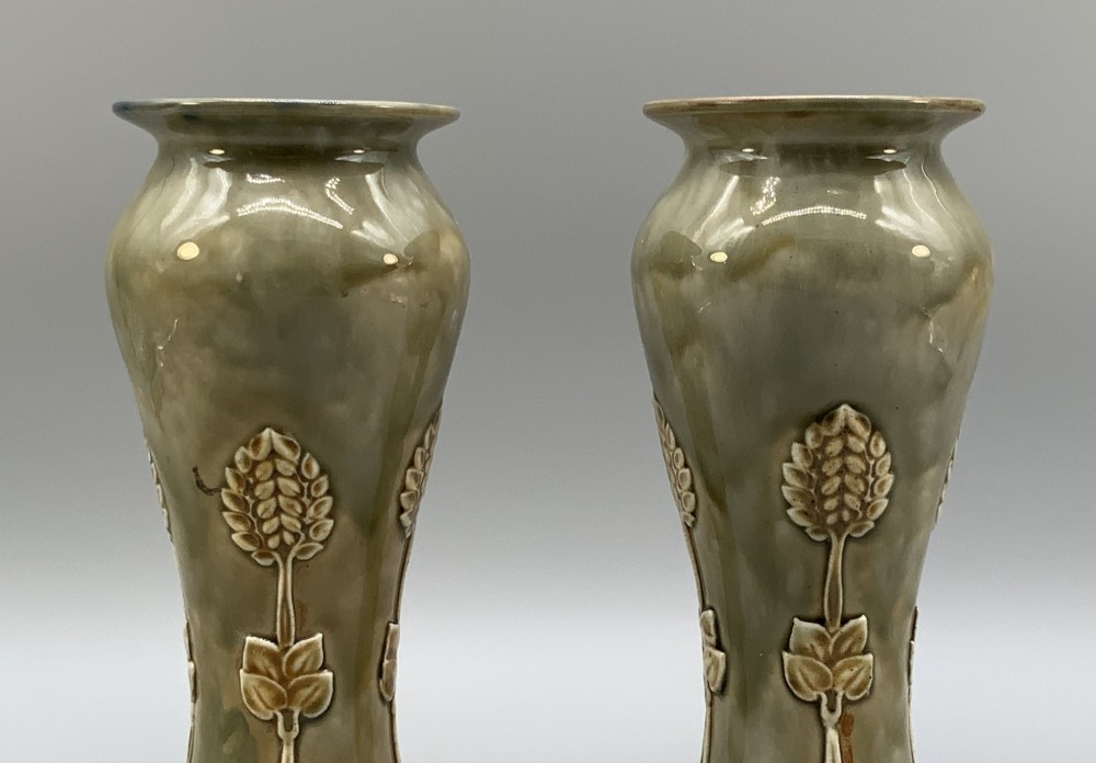 A matched pair of Royal Doulton Lambeth Art Nouveau stoneware vases featuring raised relief botanical motifs on a muted olive green glazed ground. View V