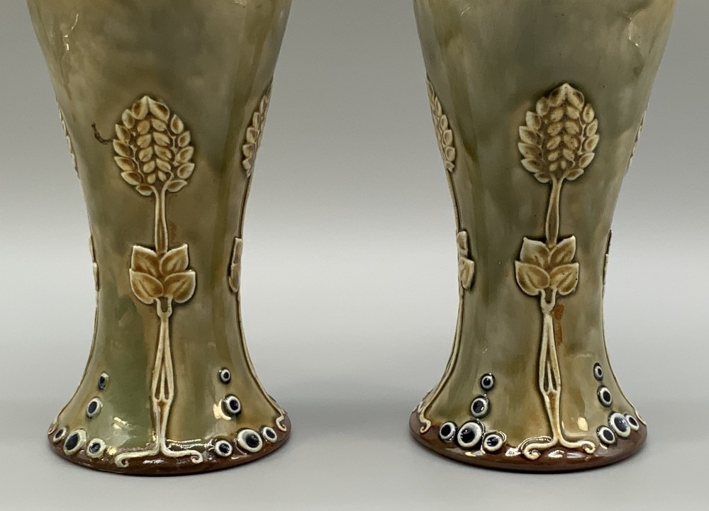 A matched pair of Royal Doulton Lambeth Art Nouveau stoneware vases featuring raised relief botanical motifs on a muted olive green glazed ground. View VI