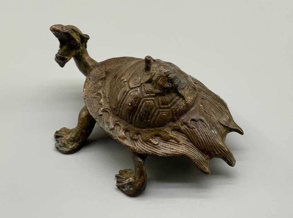 A small Japanese Meiji period bronze sculpture of a minogame turtle with a smaller turtle perched on its shell.