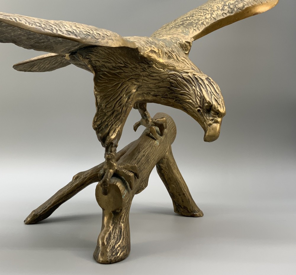 A cast brass sculpture depicting an eagle with outstretched wings perched atop a detailed log branch. View VI