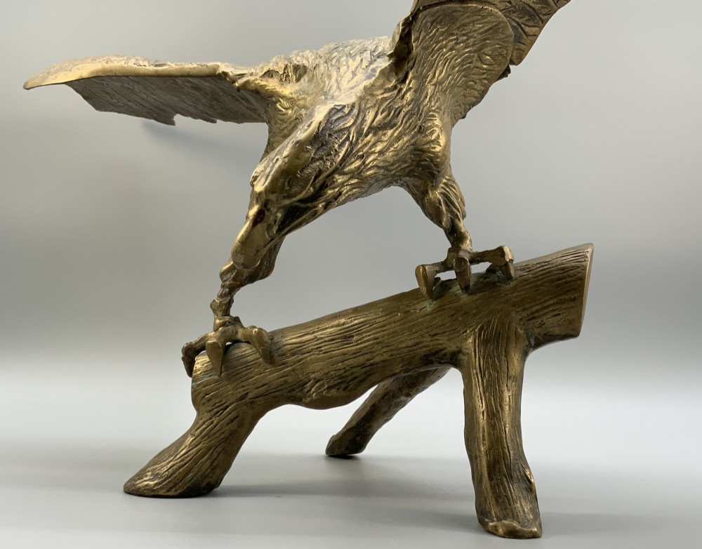 A cast brass sculpture depicting an eagle with outstretched wings perched atop a detailed log branch. View X
