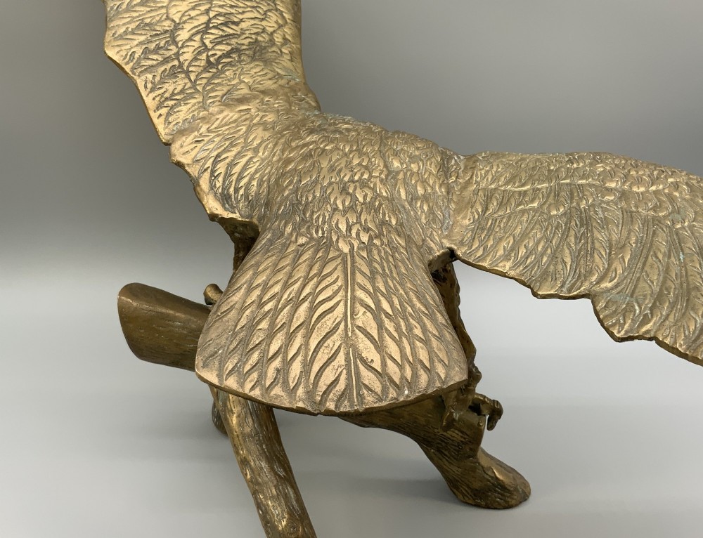 A cast brass sculpture depicting an eagle with outstretched wings perched atop a detailed log branch. View XII