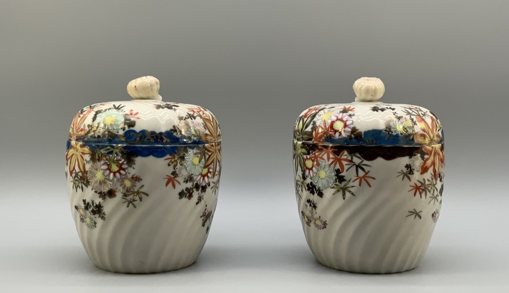A pair of 19th-century Japanese cream porcelain lidded jars featuring spiralled fluted bodies and hand-painted polychrome floral decoration with sculpted finials. View IV