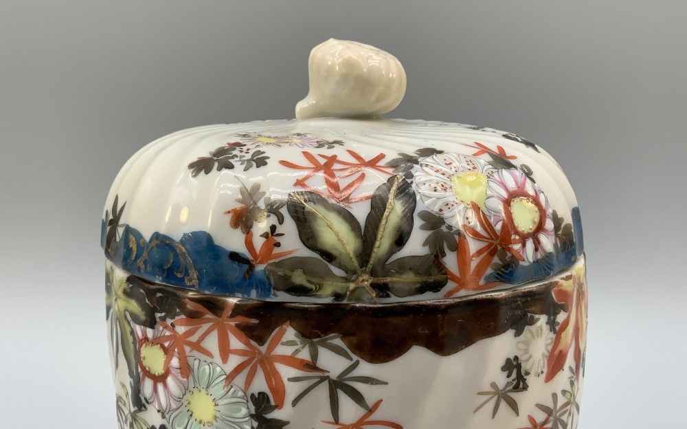 A pair of 19th-century Japanese cream porcelain lidded jars featuring spiralled fluted bodies and hand-painted polychrome floral decoration with sculpted finials. View VIII