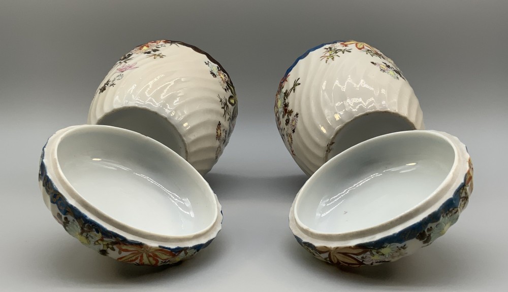 A pair of 19th-century Japanese cream porcelain lidded jars featuring spiralled fluted bodies and hand-painted polychrome floral decoration with sculpted finials. View IX
