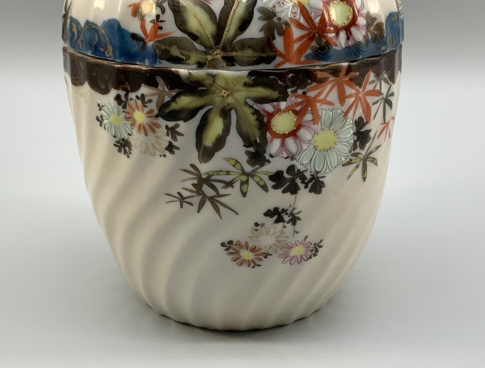 A pair of 19th-century Japanese cream porcelain lidded jars featuring spiralled fluted bodies and hand-painted polychrome floral decoration with sculpted finials. View XI