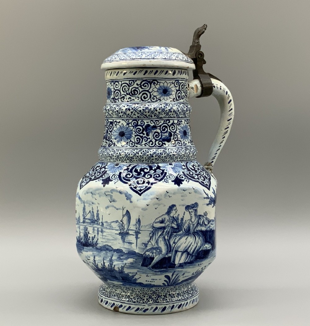 An eighteenth-century blue and white Dutch Delftware ceramic jug decorated with hand-painted figures, complete with a fitted pewter lid.