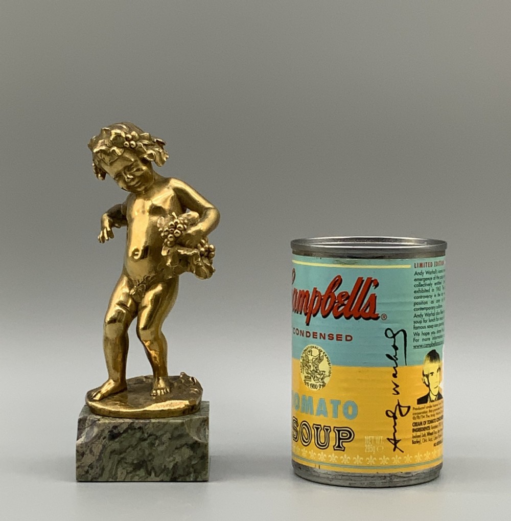 A small gilt bronze sculpture depicting an infant Bacchus holding a bunch of grapes, set upon a square green marble plinth. View III