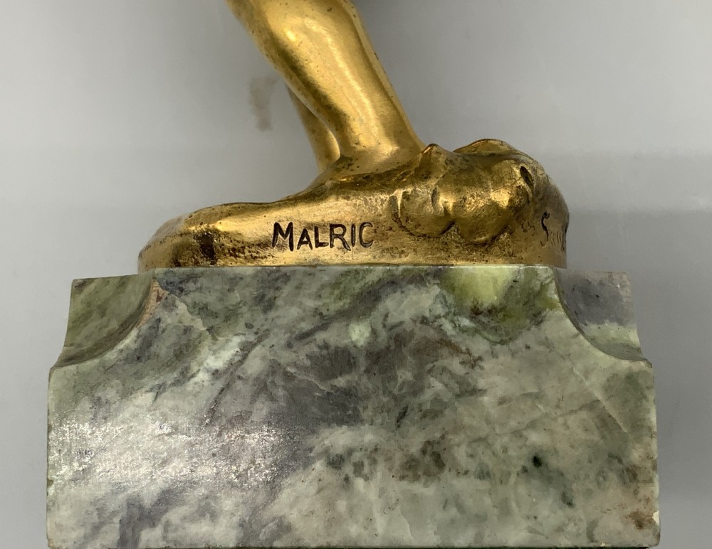 A small gilt bronze sculpture depicting an infant Bacchus holding a bunch of grapes, set upon a square green marble plinth. View XII