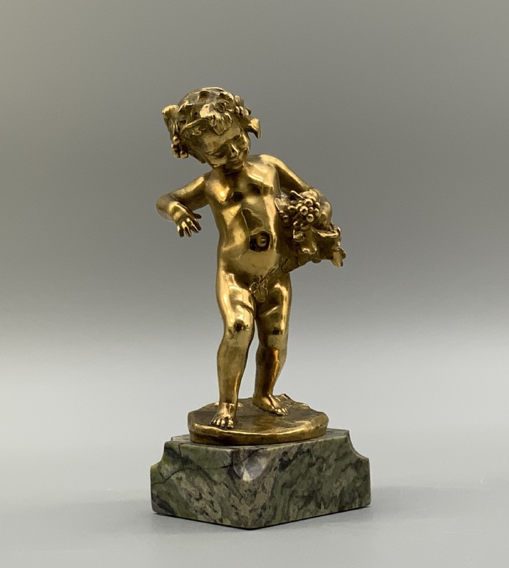 A small gilt bronze sculpture depicting an infant Bacchus holding a bunch of grapes, set upon a square green marble plinth. View XIII