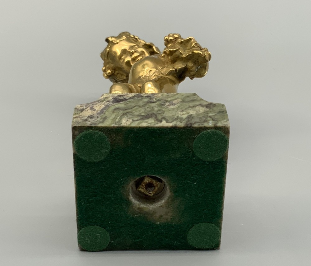 A small gilt bronze sculpture depicting an infant Bacchus holding a bunch of grapes, set upon a square green marble plinth. View XIV