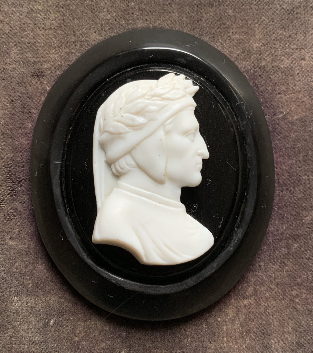 A small carved white classical profile portrait cameo mounted on a dark background within a deep black ebonised square frame. View IV