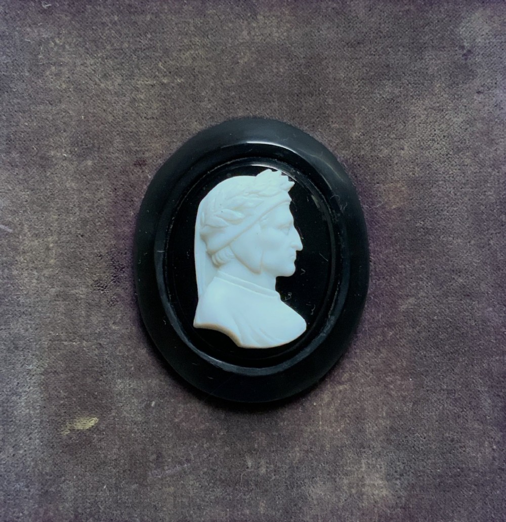 A small carved white classical profile portrait cameo mounted on a dark background within a deep black ebonised square frame. View V