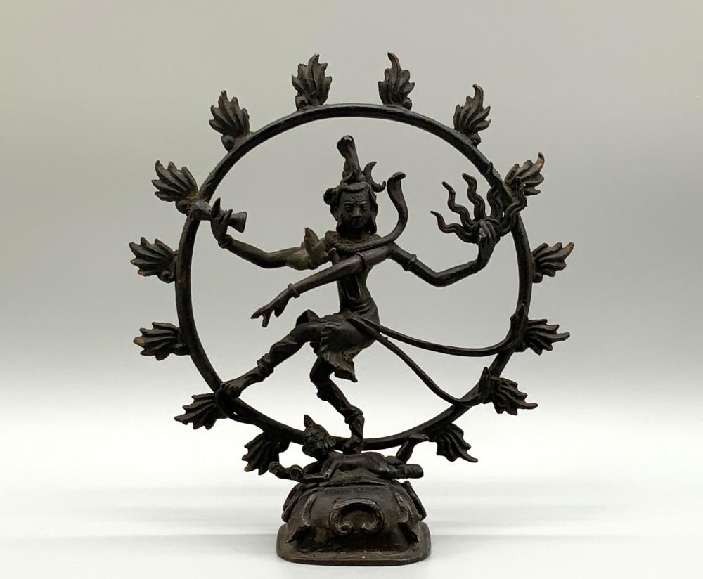 A dark patinated bronze 19th-century figure of Shiva Nataraja dancing within a circular halo of flames atop a lotus pedestal.