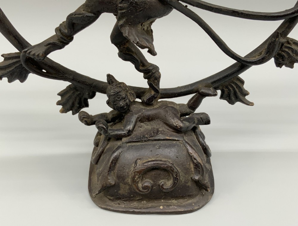 A dark patinated bronze 19th-century figure of Shiva Nataraja dancing within a circular halo of flames atop a lotus pedestal. View V