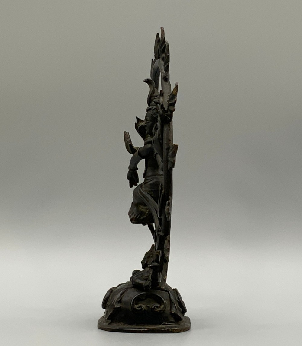 A dark patinated bronze 19th-century figure of Shiva Nataraja dancing within a circular halo of flames atop a lotus pedestal. View VIII
