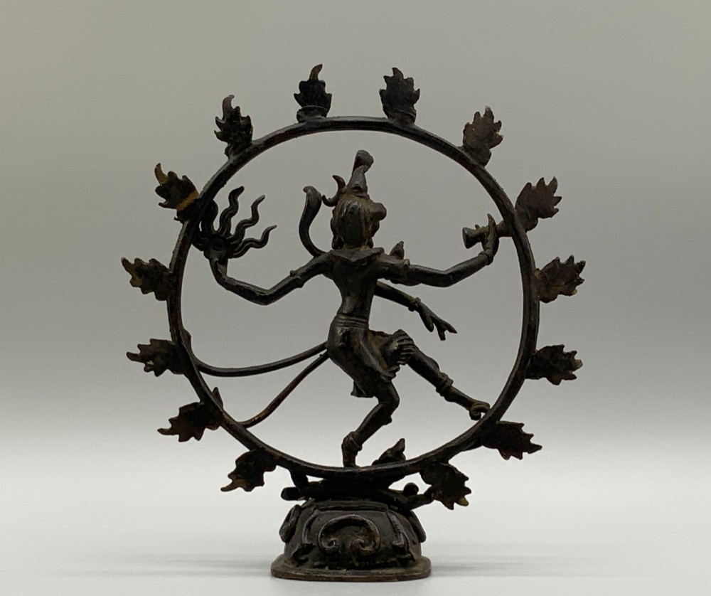 A dark patinated bronze 19th-century figure of Shiva Nataraja dancing within a circular halo of flames atop a lotus pedestal. View X