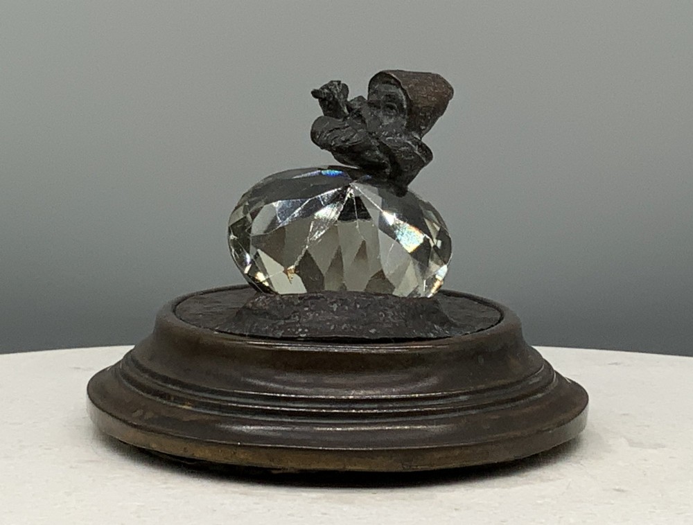 A small dark bronze figurine of a bearded dwarf miner holding a hammer overhead, standing on a molded base next to a faceted cut crystal gem. View VI