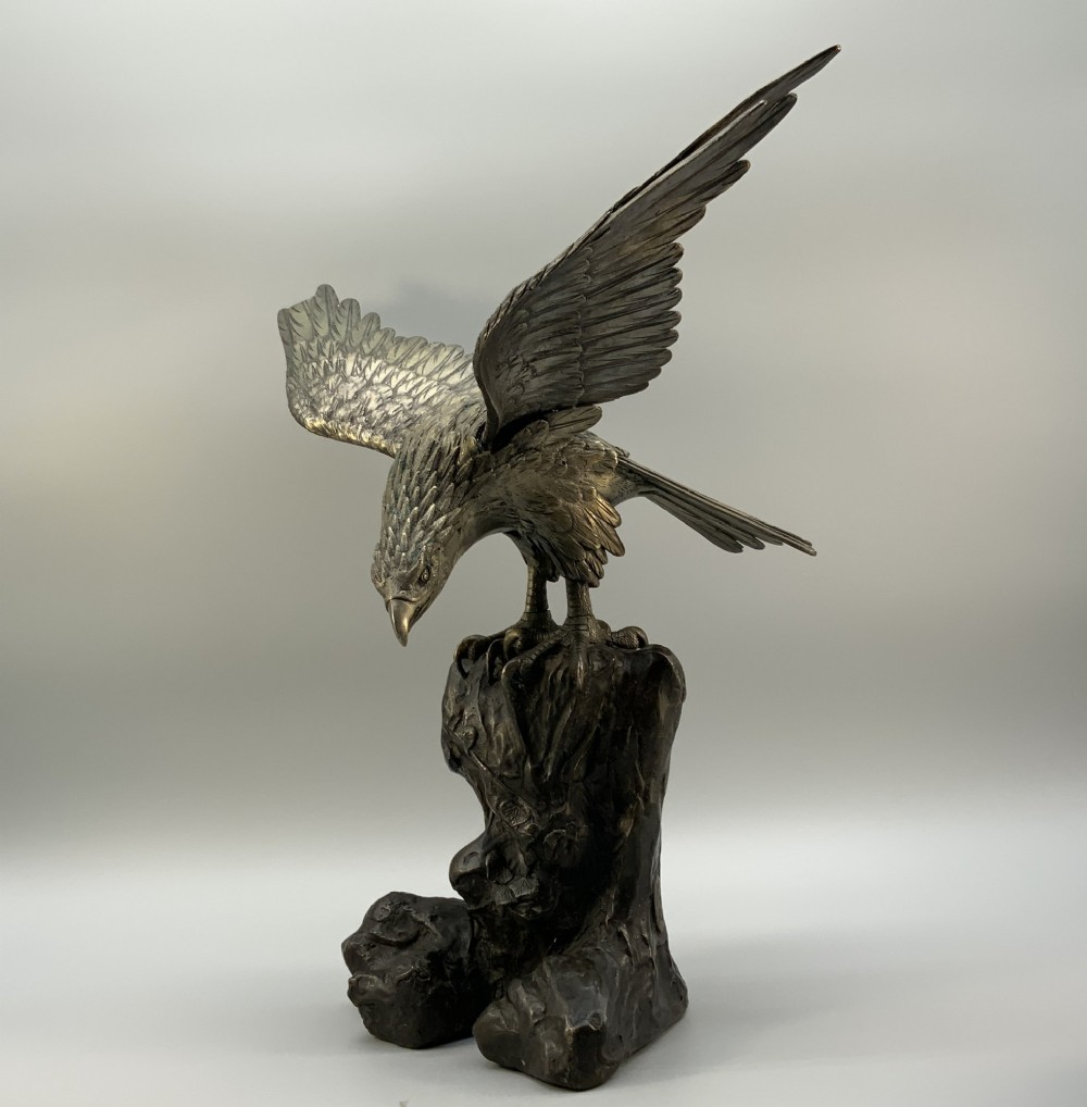 A Japanese Meiji period patinated bronze sculpture depicting an eagle perched on a rocky base with outspread wings. View IX