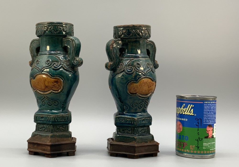 A pair of early seventeenth-century Chinese ceramic vases featuring turquoise glaze, amber reserves, relief scrollwork, and wooden bases. View V
