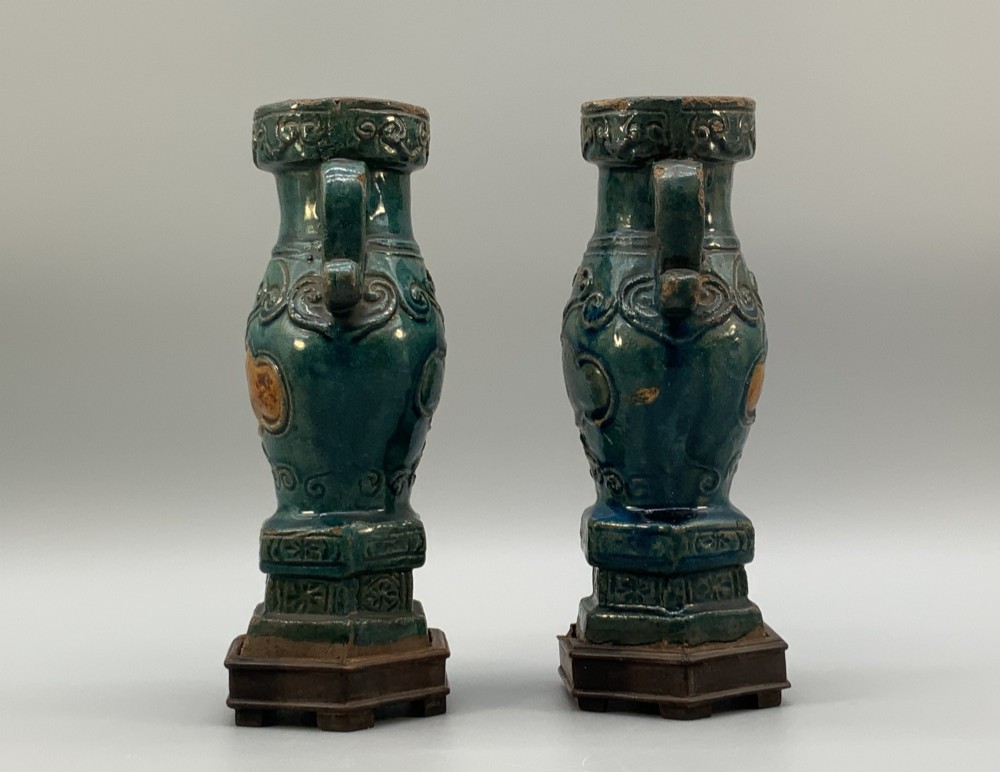 A pair of early seventeenth-century Chinese ceramic vases featuring turquoise glaze, amber reserves, relief scrollwork, and wooden bases. View VI