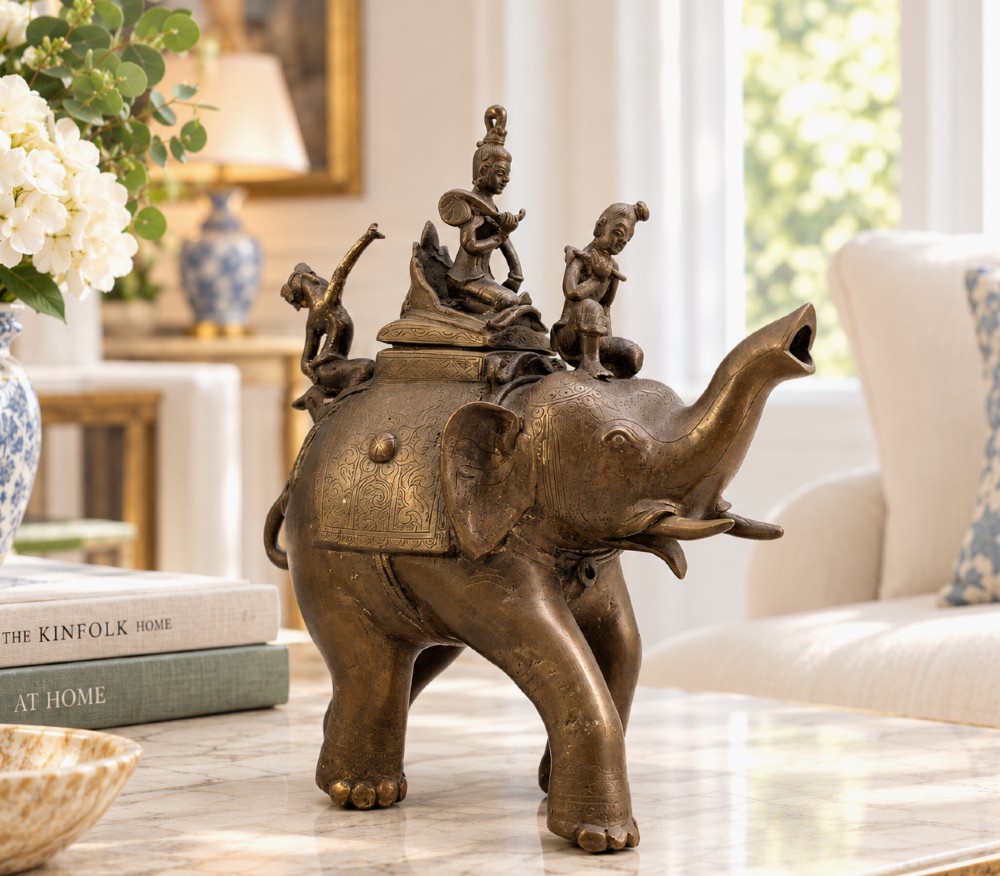 A dark bronze 19th-century sculpture depicting an elephant with engraved decorative trappings and riders seated on its back. View II
