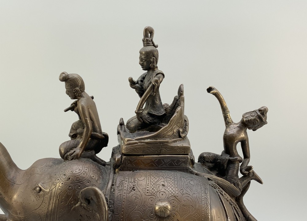 A dark bronze 19th-century sculpture depicting an elephant with engraved decorative trappings and riders seated on its back. View V