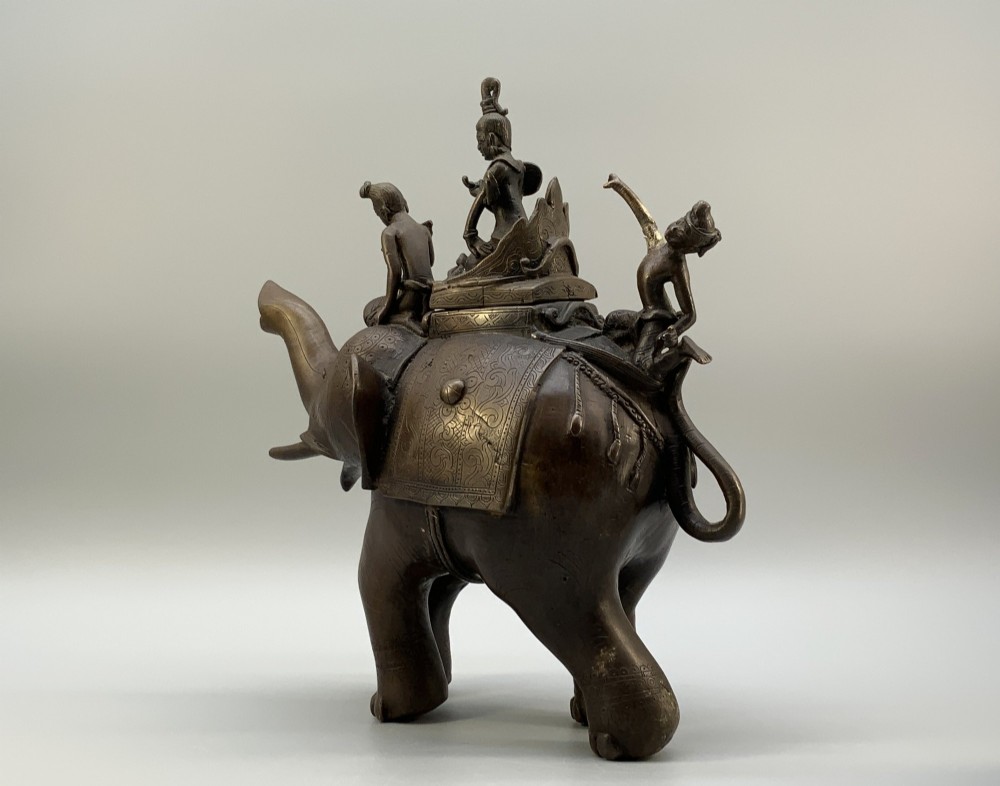 A dark bronze 19th-century sculpture depicting an elephant with engraved decorative trappings and riders seated on its back. View VI