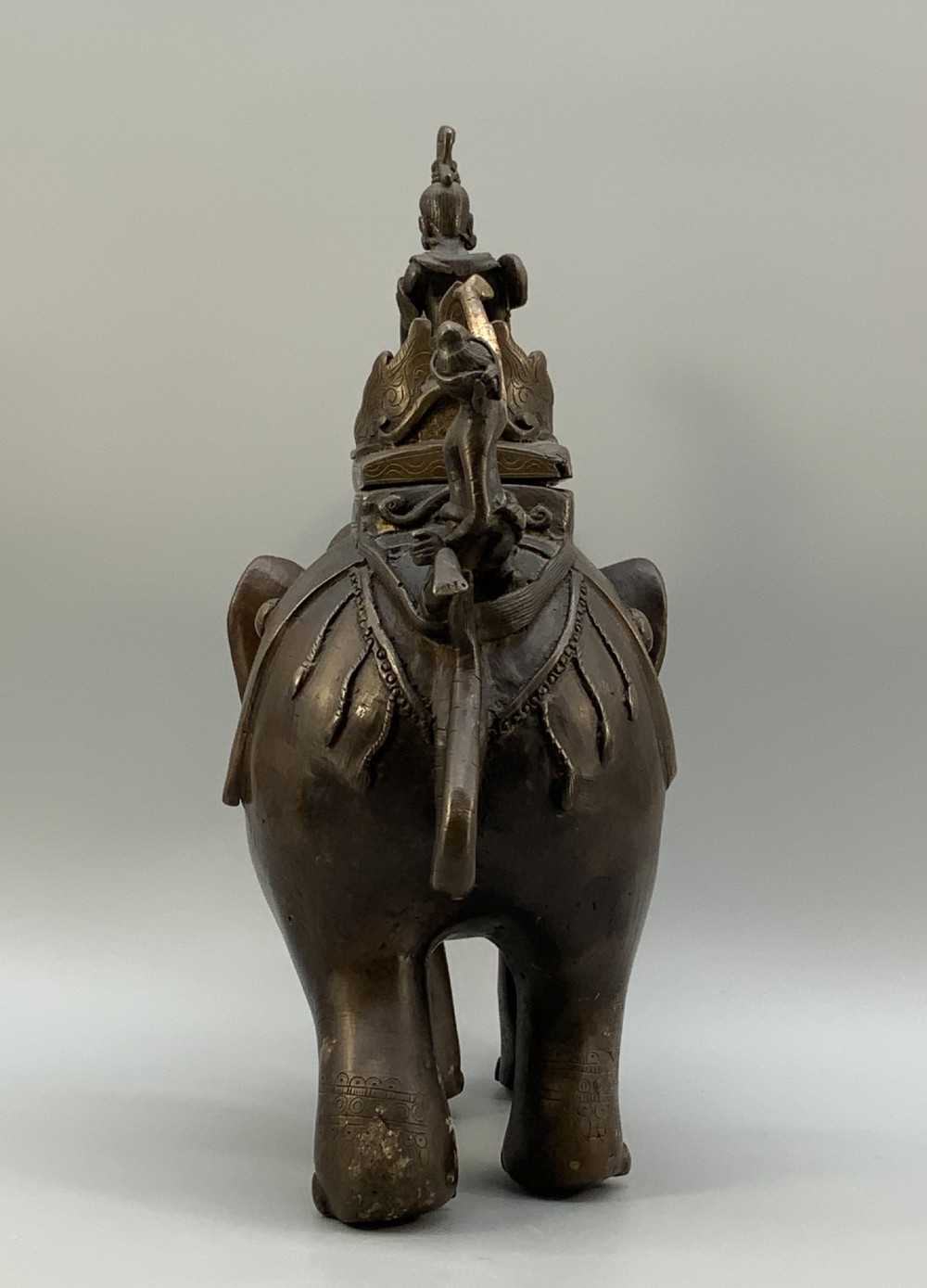 A dark bronze 19th-century sculpture depicting an elephant with engraved decorative trappings and riders seated on its back. View VII