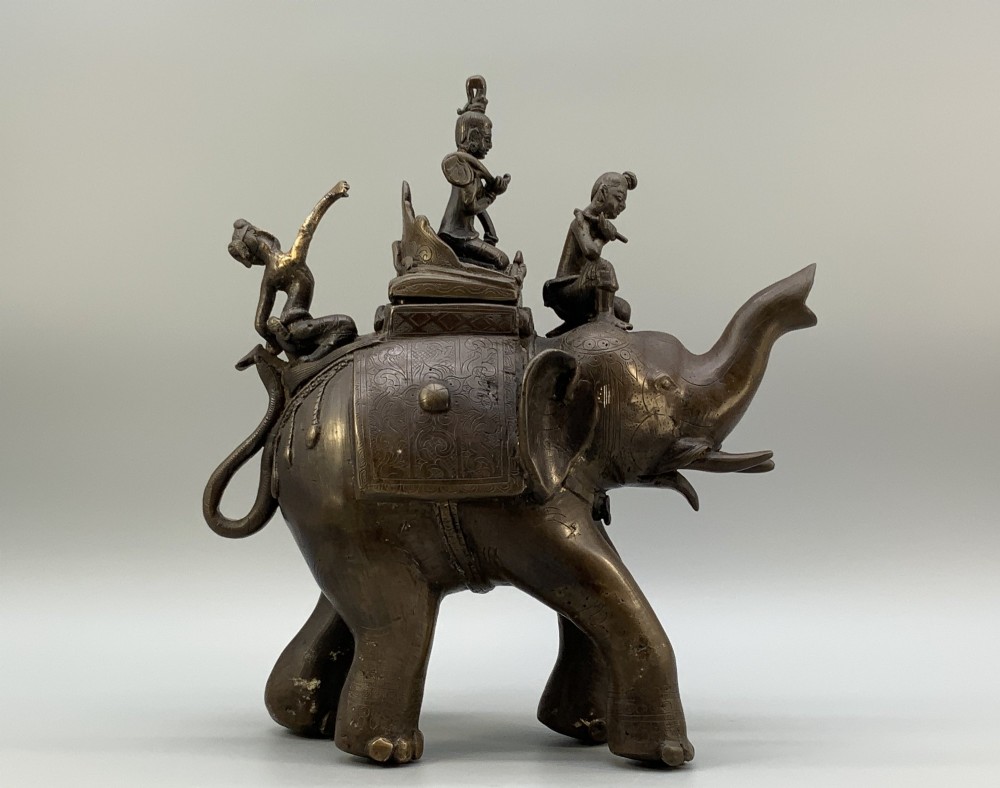 A dark bronze 19th-century sculpture depicting an elephant with engraved decorative trappings and riders seated on its back. View VIII