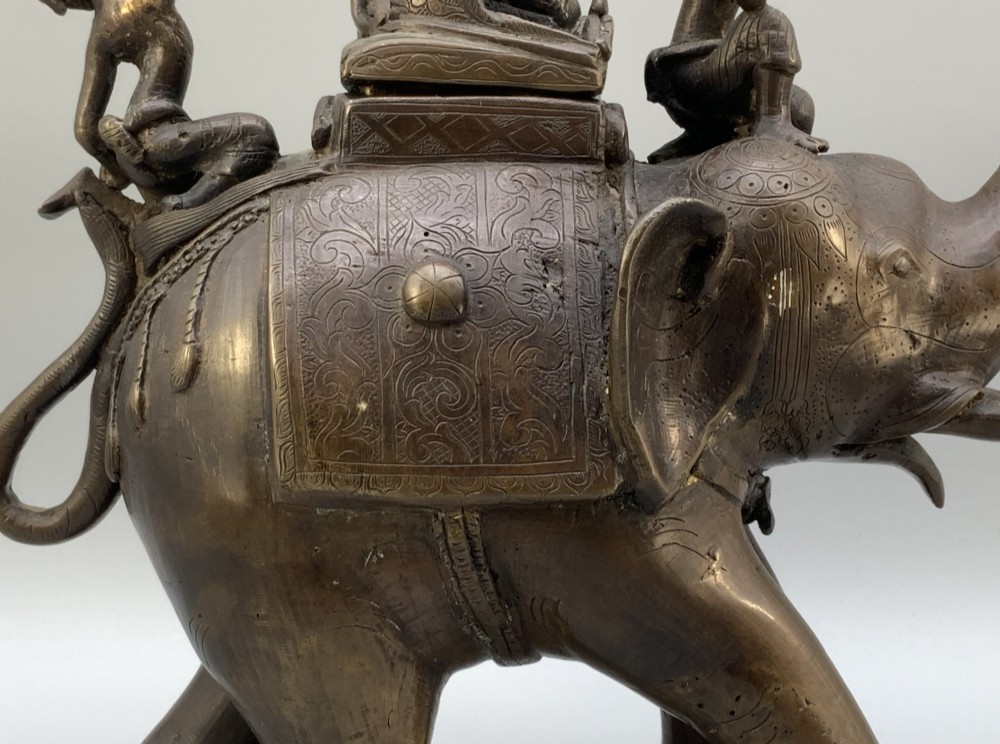 A dark bronze 19th-century sculpture depicting an elephant with engraved decorative trappings and riders seated on its back. View IX