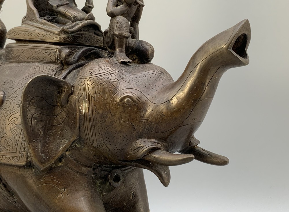 A dark bronze 19th-century sculpture depicting an elephant with engraved decorative trappings and riders seated on its back. View XII