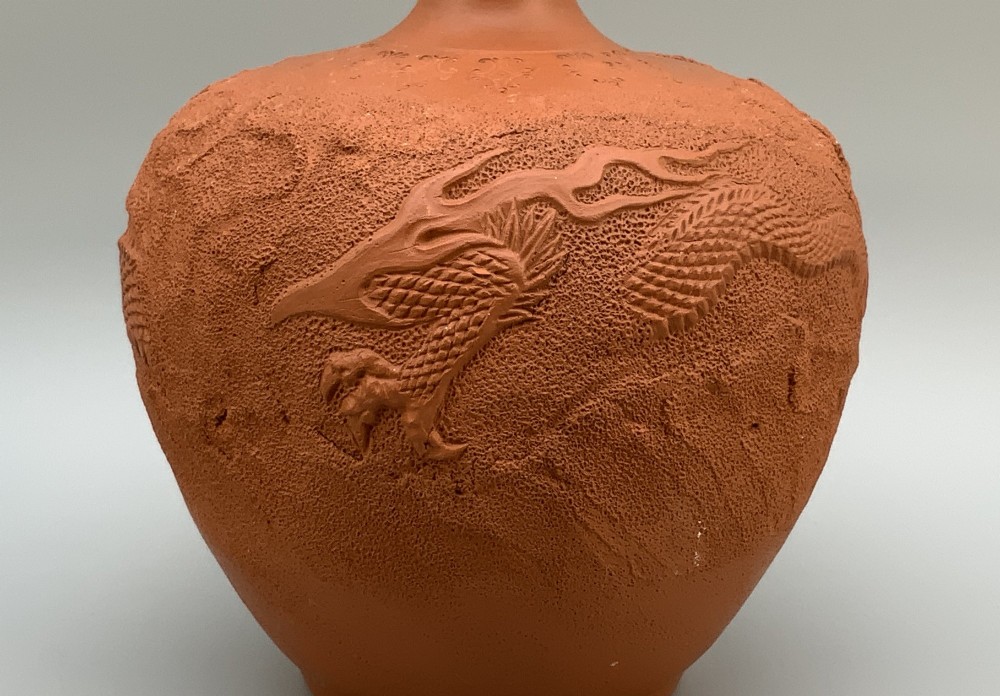 A pair of unglazed terracotta red clay vases featuring detailed relief carvings of dragons with narrow flared necks. View VI