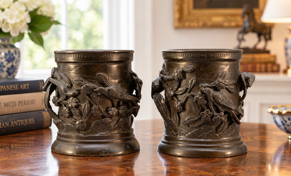 A pair of cylindrical dark patinated bronze vases featuring raised relief depictions of birds perched amongst cherry blossom branches. View II