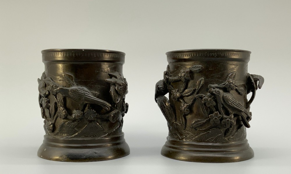 A pair of cylindrical dark patinated bronze vases featuring raised relief depictions of birds perched amongst cherry blossom branches. View XI