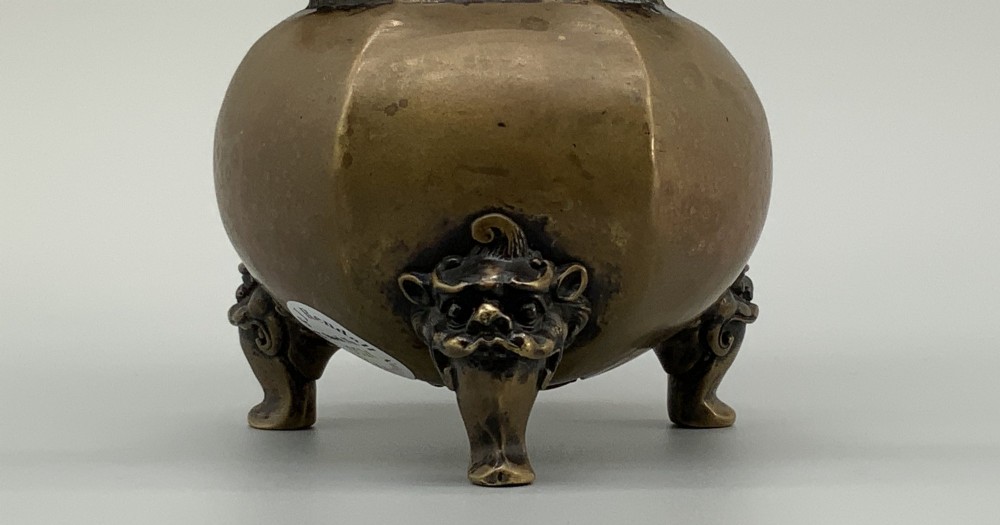A late Qing dynasty hexagonal bronze tripod censer featuring upright side handles, a removable cover topped with a mythical beast finial, and feet shaped as animal masks. View V