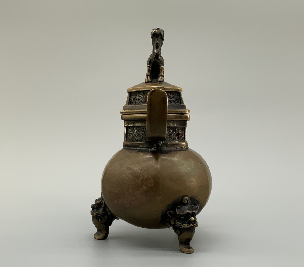 A late Qing dynasty hexagonal bronze tripod censer featuring upright side handles, a removable cover topped with a mythical beast finial, and feet shaped as animal masks. View VII