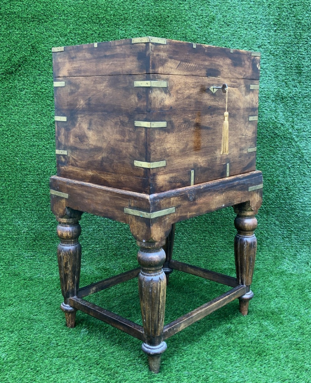 A dark teak Anglo-Indian wine cellarette box with brass corner mounts resting on a carved turned-leg wooden stand. View III