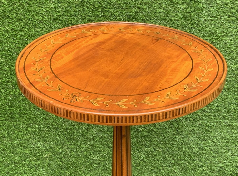 A 19th-century satinwood wine table featuring a circular top with inlaid marquetry detailing, supported by a fluted central pedestal and three downswept tripod legs. View V