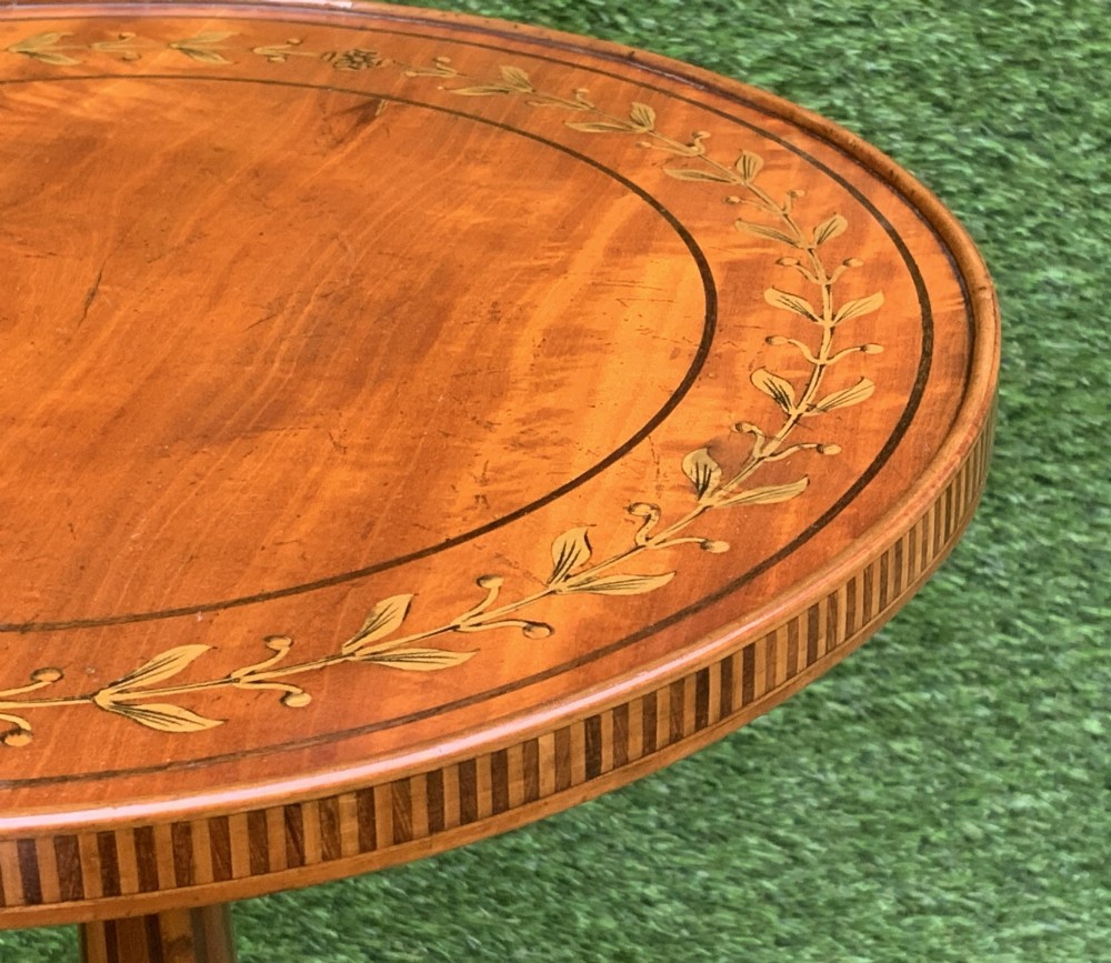 A 19th-century satinwood wine table featuring a circular top with inlaid marquetry detailing, supported by a fluted central pedestal and three downswept tripod legs. View IX