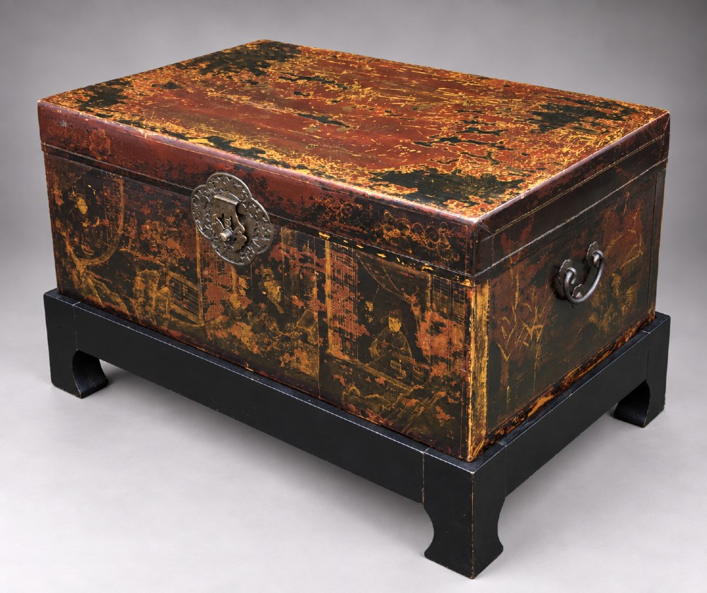 A large rectangular Japanese lacquered storage chest with gilt figurative Chinoiserie scenes set upon a black painted wooden stand.
